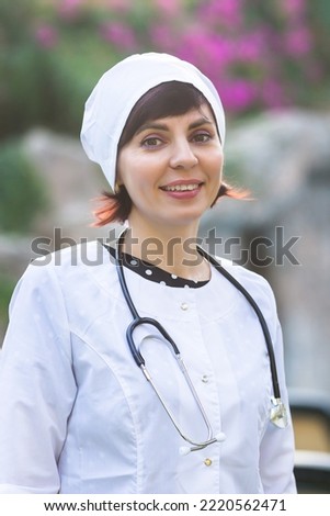 Portrait of a female doctor in working clothes on a background of nature.