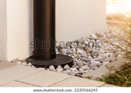 French drain Water Drainage pipe with water Stones Gravel aroud House   Royalty-Free Stock Photo #2220566245