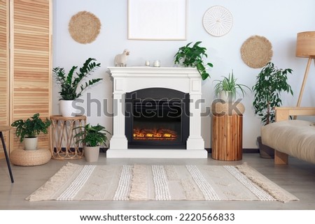 Beautiful living room interior with fireplace, green houseplants and comfortable sofa