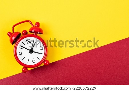Red vintage alarm clock on bright red and yellow background with empty space for your text or message.