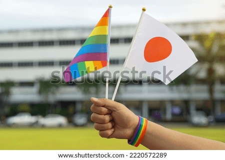  Rainbow flag and the national flag of Japan Hold it in the hands of LGBT people wearing rainbow wristbands. soft and selective focus.                                Royalty-Free Stock Photo #2220572289