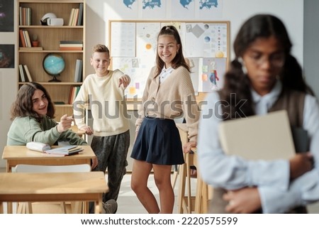 Group of pre-teen Caucasian schoolkids bullying African American classmate, pointing at her and making fun of her Royalty-Free Stock Photo #2220575599