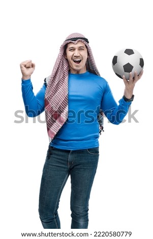 Asian man with keffiyeh standing while holding the ball with a happy expression isolated over white background