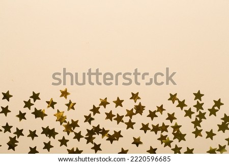 Golden confetti stars on color background, top view.