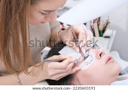 Master applies lash dye to eyelashes. Close-up of beauty model's face during lash extension procedure. Eyelash Care Treatment. eyelash lamination and extension