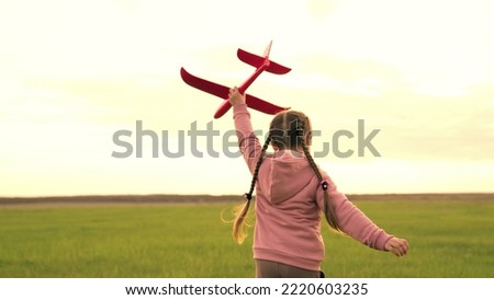 little girl runs sunset with toy plane her hand. kid child run around green field sunset playing toy plane. childhood dream becoming pilot. little superhero child. children run park. happy girl pilot.