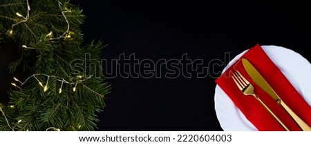 Christmas of table setting and ring or wreath with glowing garland on the black background. Copy space.