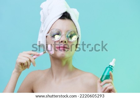  Horizontal photo, a woman with gorgeous skin on a blue background in a towel on her head and body and luxurious glasses and patches on her lips takes care of her face