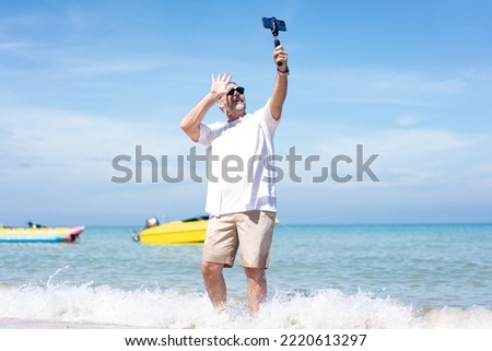  Man taking selfie of himself after workout. Good looking taking a self-portrait picture with his smartphone camera on a beach during summer vacation travel.