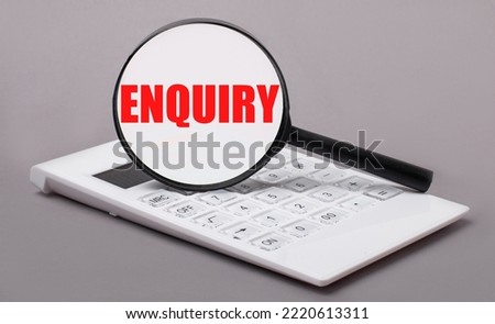On a gray background, a white calculator and a magnifying glass with the text ENQUIRY. Business concept