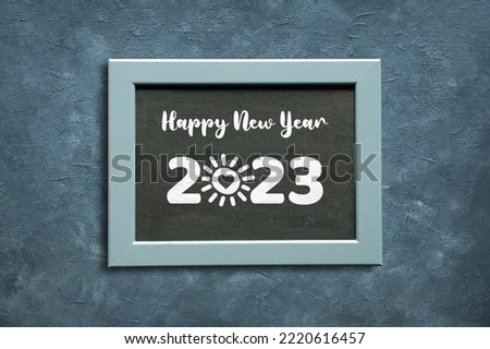 Happy New Year 2023, sun with heart cartoon drawn in place of zero digit. Flat lay, top view on dark green textured background.