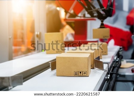 Cardboard boxes on conveyor, robotic arm picked up the blurry box. parcel delivery system concept.      Royalty-Free Stock Photo #2220621587