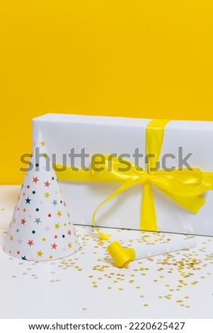 Vertical image of holiday gifts - box with wrapping, cap and party horn. An idea for decorating your holiday, a greeting card
