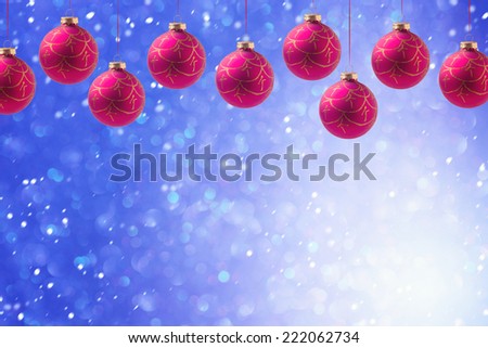 Christmas balls hanging over blue bokeh background with copy space