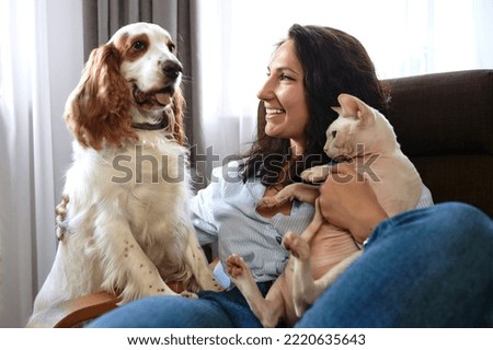 A woman lies on a sofa with a cat and a dog. Love for pets concept