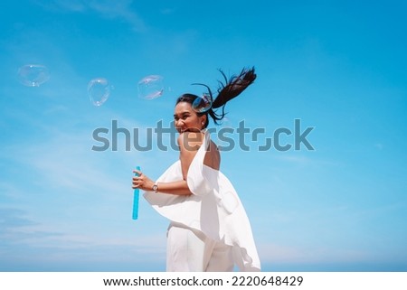 Happy beautiful young asian woman blowing soap bubbles feeling having fun enjoy on the sky background outdoors.
