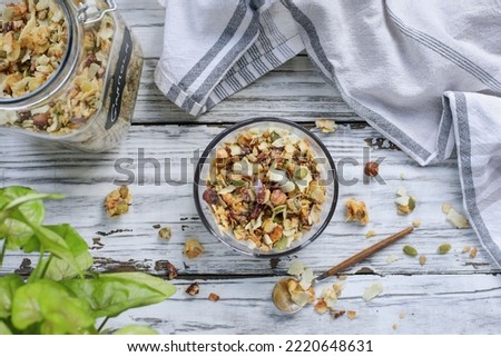 Vegan keto Granola made with pecans, hazelnuts, unsweetened coconut, sunflower seeds, pepita seeds and sweetened with erythritol. Served with low carb almond milk. Top view flatlay over a wooden table