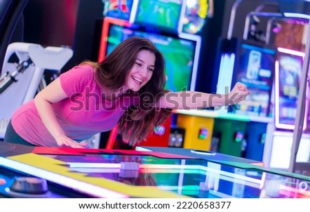 Young cheerful girl having fun, playing games at arcade entertainment center.  Royalty-Free Stock Photo #2220658377