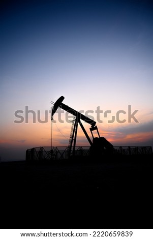 Silhouette of oil pump from oil field at sunset 