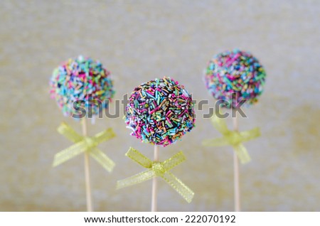 Cake pops with colorful sprinkles on golden background 