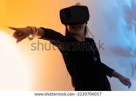 Teenage girls are having fun playing VR glasses virtual reality metaverse playing games, watching movies, listening to music, shopping. Colorful neon futuristic backgrounds, digital future technology.