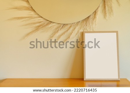 Natural wood frame with empty space for text or design on beige wall and dried flowers background