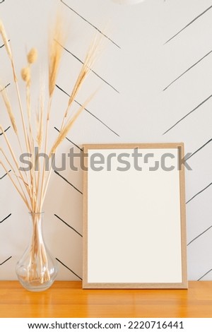 wooden frame with place for design stand on table near vase with natural dried flowers