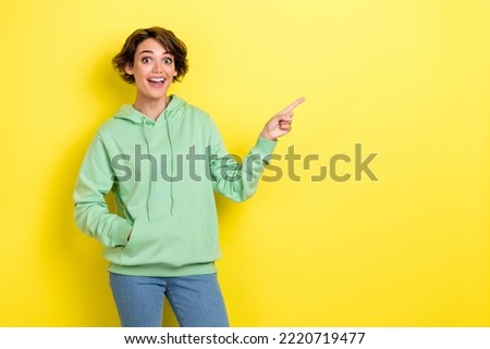 Photo portrait of pretty young girl excited point empty space unbelievable dressed stylish green look isolated on yellow color background