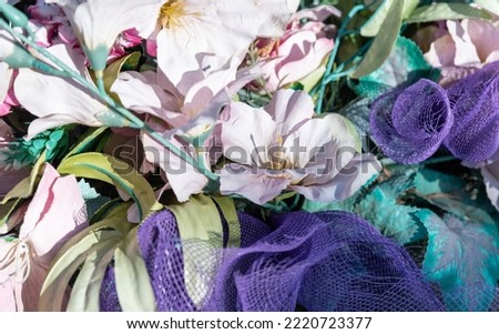 Bunches of artificial flowers in close-up. Faded artificial flowers on the grave. Colorful flowers on the grave.