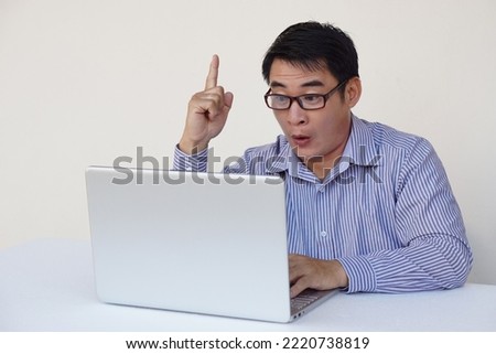 Handsome Asian man office worker feels surprised and got the idea during surfing internet on laptop computer. Point finger up. Concept : work online. Daily Life digital, technology smart device.     