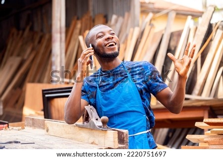 image of excited african man with smart phone in a workshop Royalty-Free Stock Photo #2220751697