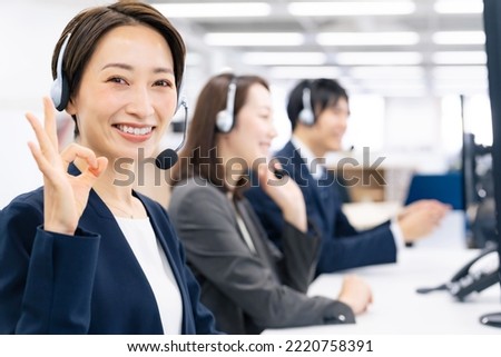 Asian operator in call center showing OK hand sign.