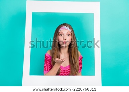 Photo of pretty adorable school girl dressed pink crop top sending kiss photographing white paper frame isolated teal color background