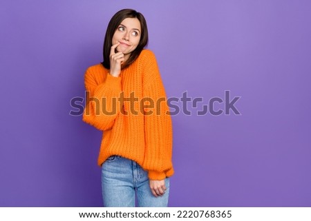 Photo of cute young woman shy finger touch face look empty space wondered dressed orange knitted look isolated on purple color background