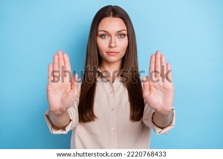 Photo portrait of pretty young lady stretching arms making sign stop dressed trendy smart casual outfit isolated on blue color background