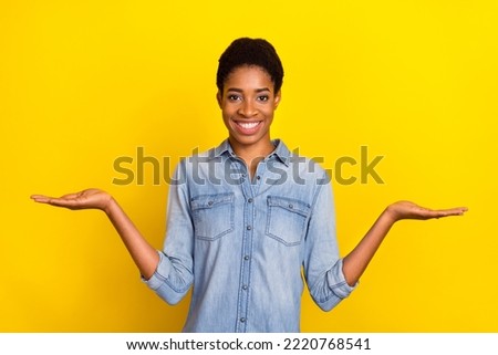 Portrait of cheerful person arms palms demonstrate empty space vs scales isolated on yellow color background