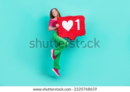 Full length photo of cute adorable school girl dressed pink crop top flared pants jumping holding feedback pinata isolated teal color background