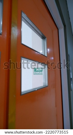 Meeting room door with an evacuation route sign sticker on the wall.Illustration of standard work safety procedures.
