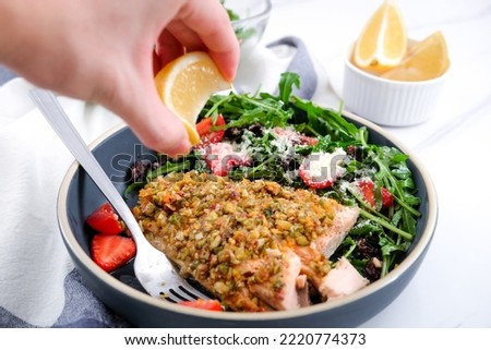 Pistachio baked crusted salmon with arugula berries and raisin salad on the side Royalty-Free Stock Photo #2220774373