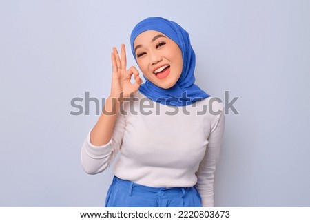 Cheerful young beautiful Asian Muslim woman showing okay sign isolated over white background