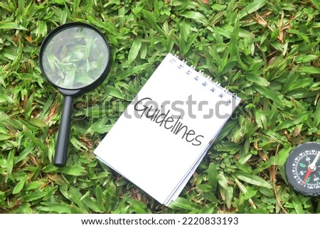 Guidelines wording on a paper with magnifying glass over a green grass background. 