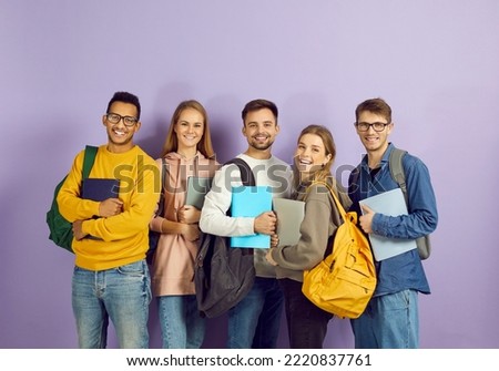 Diverse group of happy university or college students. Cheerful smiling multiethnic young friends in casual wear with backpacks, laptop PCs and class textbooks standing in studio and looking at camera