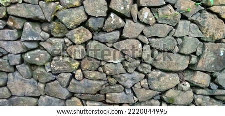Stone walls, old stone textures, stone fences or piles of rocks arranged as a parapet on the outskirts of a green forest, Indonesia.