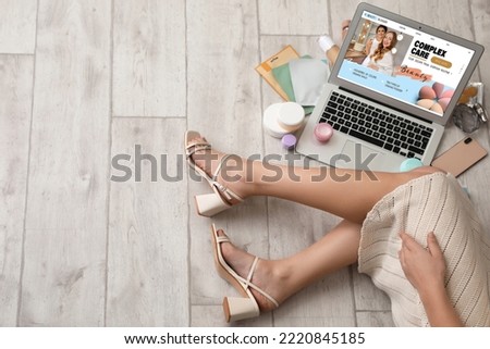 Female beauty blogger with laptop and skincare products on light wooden background