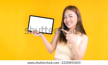 beautiful Asian young woman showing smart phone , tablet phone computer with blank screen ,white screen ,empty copy space for advertising banner isolated on on yellow background , Mock Up Image