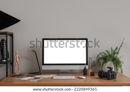 Photographer's workplace with computer and pictures near light wall in office