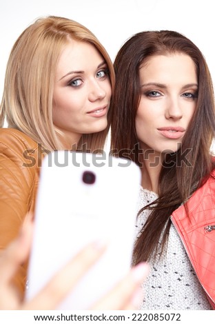 portrait of two beautiful girls making selfies at studio