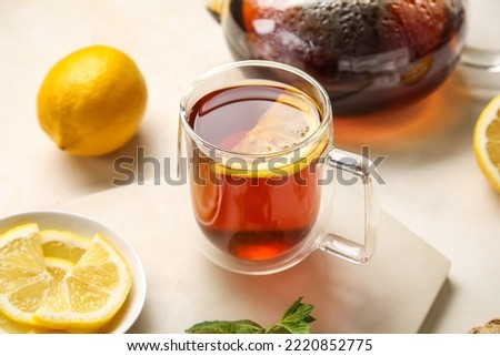 Board with glass cup of black tea and lemon on white background, closeup