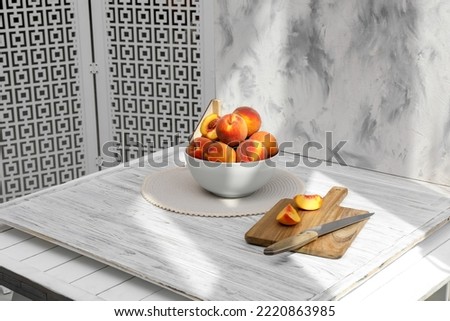 Bowl of juicy peaches and double-sided backdrop on table in photo studio