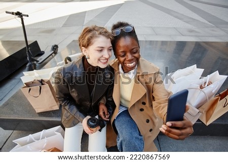 High angle portrait of two young women taking selfie photo in city downtown after shopping day